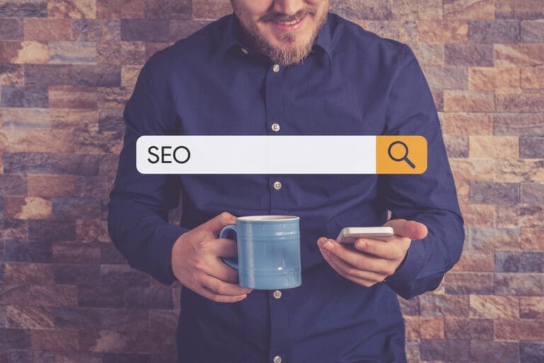Smiling man holding phone searching for something on Google